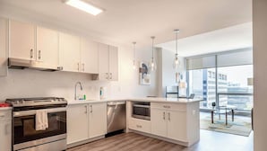 Een moderne keuken met roestvrijstalen apparatuur, witte kasten en een groot raam met uitzicht op de stad.