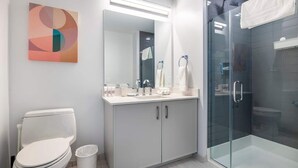 Een moderne badkamer met toilet, wastafel en douchecabine met glazen wanden.