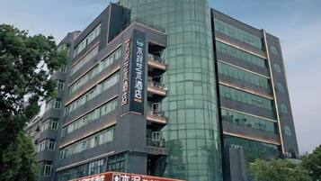 A multi-story hotel with a modern design, featuring a prominent vertical sign with text, multiple balconies, and a reflective glass facade.