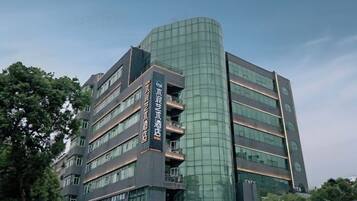 A multi-story building with a curved glass facade, multiple balconies, and signage indicating it is a hotel.