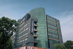 Un edificio de varios pisos con fachada de vidrio curvo, múltiples balcones y señalización que indica que es un hotel.
