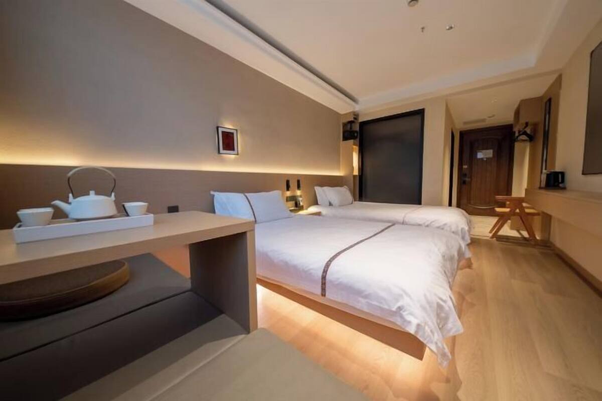 A modern hotel room with a bed, bedside table, and a small seating area.