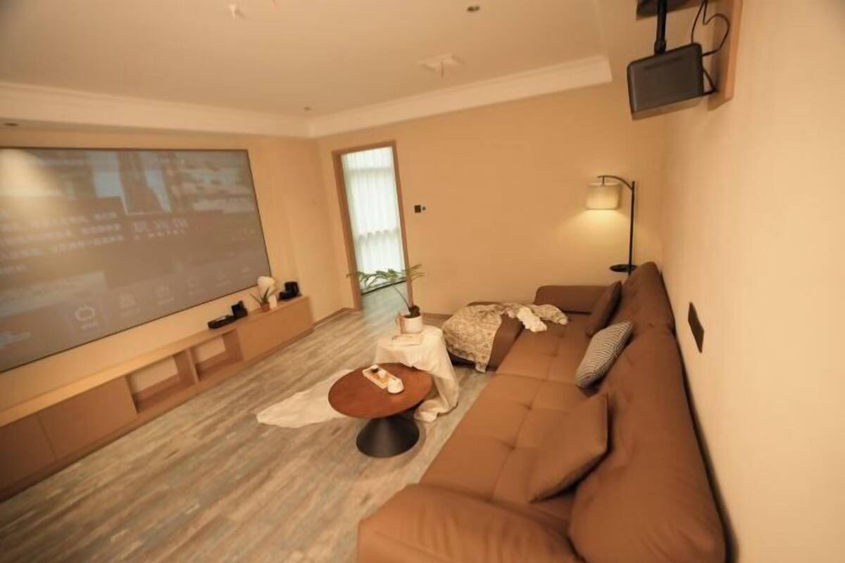 A modern living room with a large flat-screen TV, a sofa, a coffee table, and a lamp.