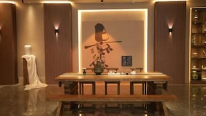 A modern hotel lobby with a wooden reception desk, a large wall-mounted sculpture, and a sign indicating the hotel name. - MONI HOTEL ARTS (Jingdezhen)