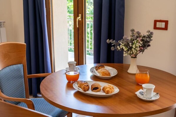 Una mesa de desayuno con croissants, jugo de naranja y un jarrón de flores.
