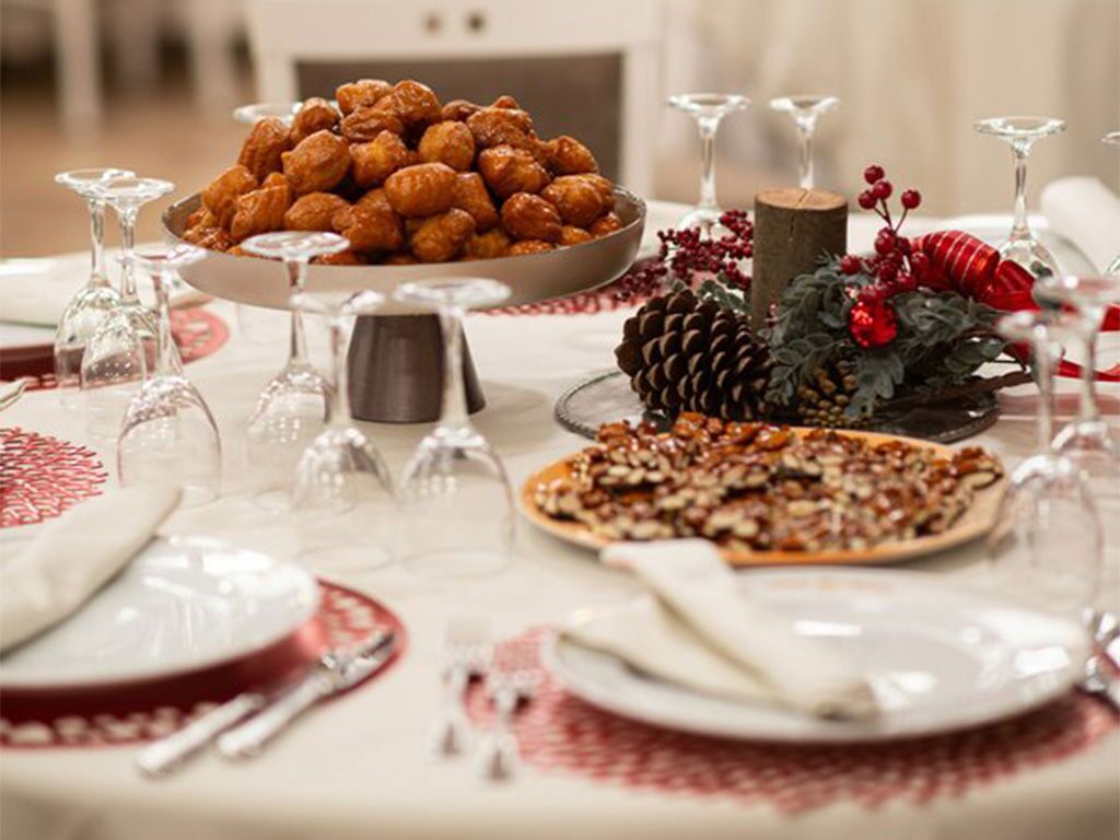 A table set for a meal with a bowl of pastries, a plate of nuts, and a pine cone decoration.