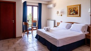 Una habitación de hotel con una cama grande, una silla, una mesa y vistas al exterior.