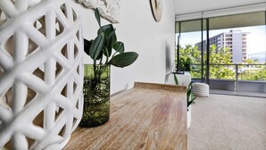 A modern room with a wooden table, a decorative white lattice, and a potted plant. - Coastal Lights I Pool, Gym & Parking@HarbourLights (Cairns City)