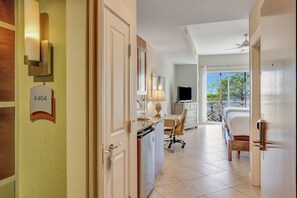 Ein Hotelzimmer mit Schreibtisch, Stuhl, Bett und einem Balkon mit Blick.