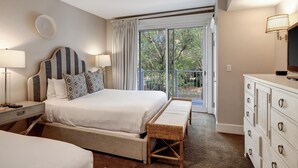 A bedroom with a large bed, a bedside table, a lamp, a bench, a dresser, and a view of the outdoors through a glass door. - Bayview Luxury: Sandestin Retreat, Resort Perks (Miramar Beach)