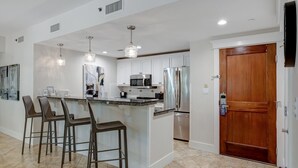 A modern kitchen with white cabinets, stainless steel appliances, and a central island with bar stools. - Bayview Luxury: Sandestin Retreat, Resort Perks (Miramar Beach)