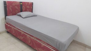 A single bed with a red headboard and grey bedding in a room with white walls and tiled flooring. - Hotel O Homestay Amanda Syariah (Makassar)
