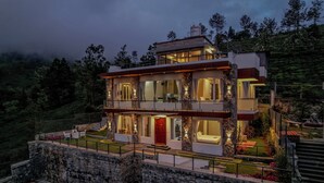 A modern two-story house with a stone foundation, a red door, and a balcony.