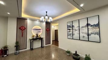 A hotel lobby with a reception desk, a chandelier, wall art, and potted plants.