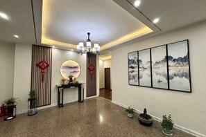 A hotel lobby with a reception desk, a chandelier, wall art, and potted plants. - Fuliang Gaoling Hotel (Fuliang)