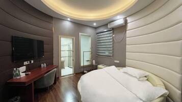 A modern hotel room with a curved ceiling, a bed, a desk, and a television.
