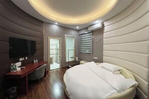 A modern hotel room with a curved ceiling, a bed, a desk, and a television. - Fuliang Gaoling Hotel (Fuliang)
