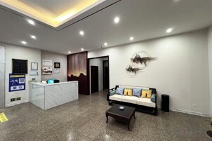 Zona de recepción con mostrador de mármol, sofá con cojines, una mesa de centro y una obra de arte abstracto en la pared.