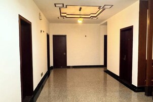 Un pasillo con piso pulido, puertas de madera oscura y un diseño geométrico en el techo.