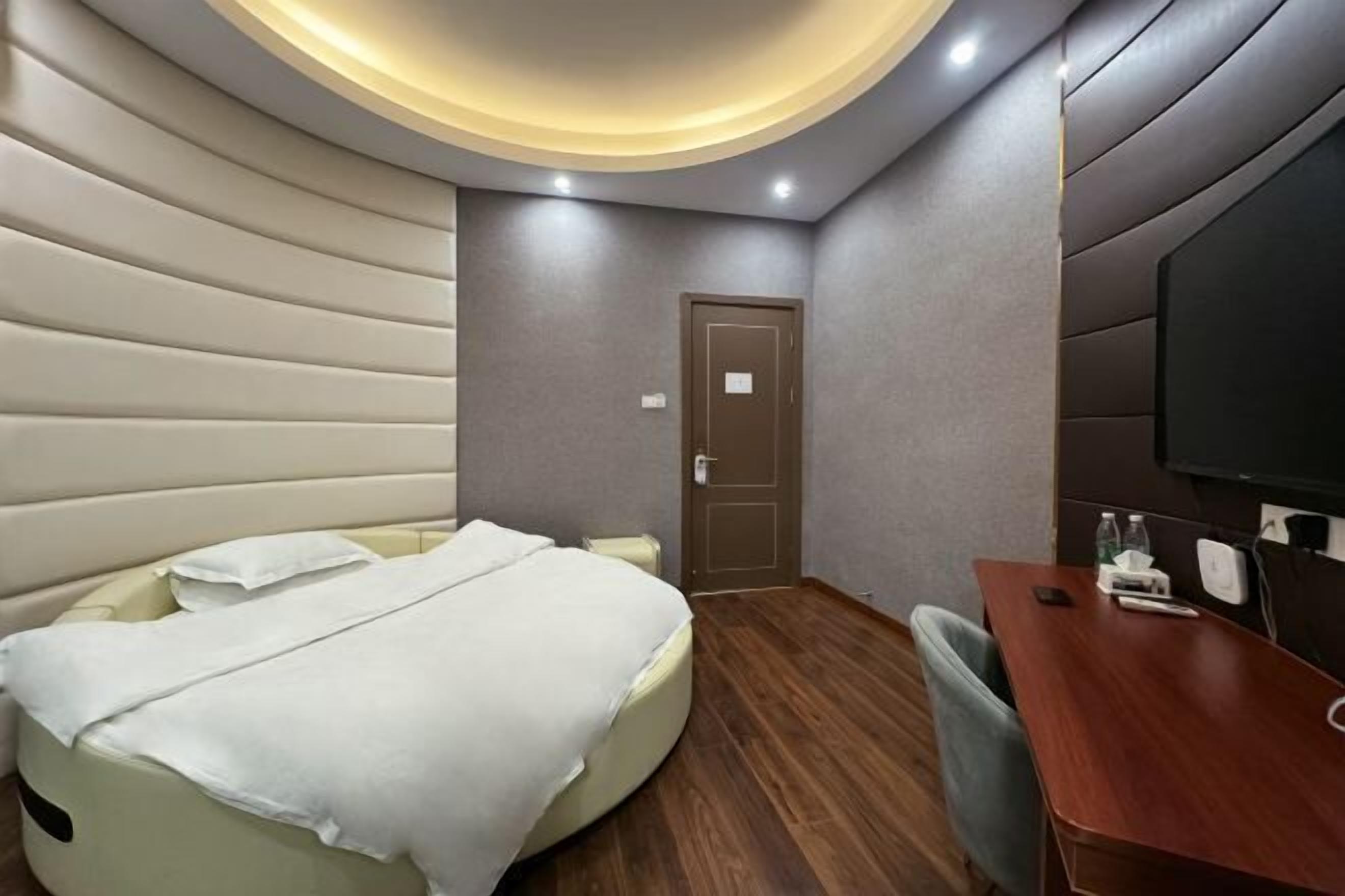 Quarto de hotel moderno com cama, escrivaninha e televisão.