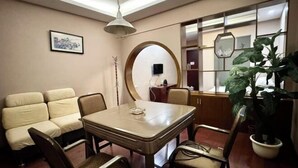 Un comedor con una mesa redonda, sillas, un sofá, una planta en maceta y un espejo.