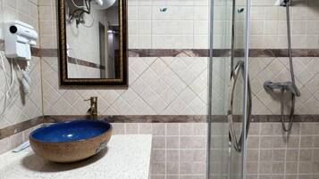 Un baño con un lavabo de cerámica azul, un espejo y un box de ducha de vidrio.