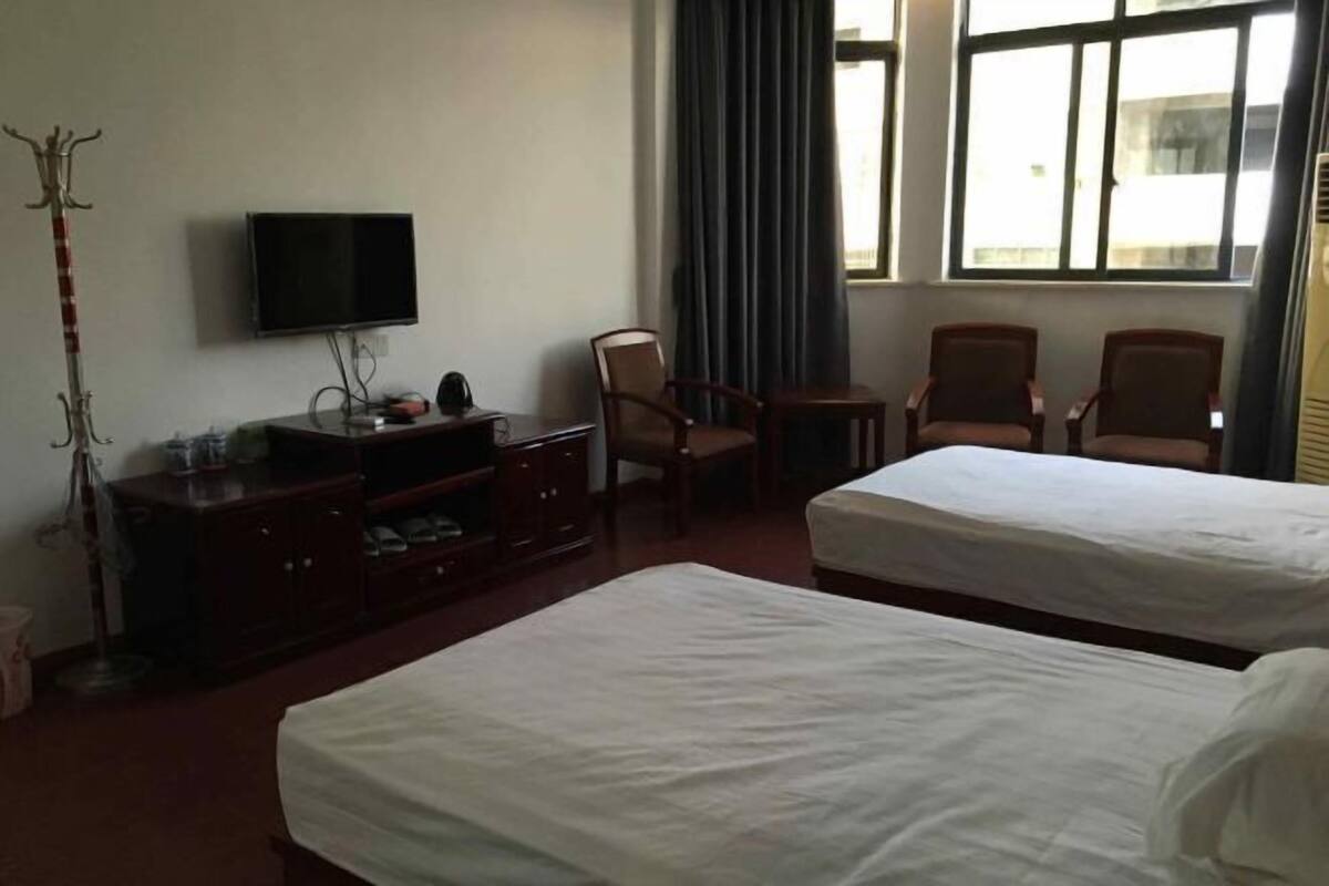 A hotel room with two beds, a TV, a desk, and a chair.