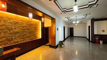 Recepció d'hotel amb taulell d'informació, paret amb un disseny i un llarg passadís.