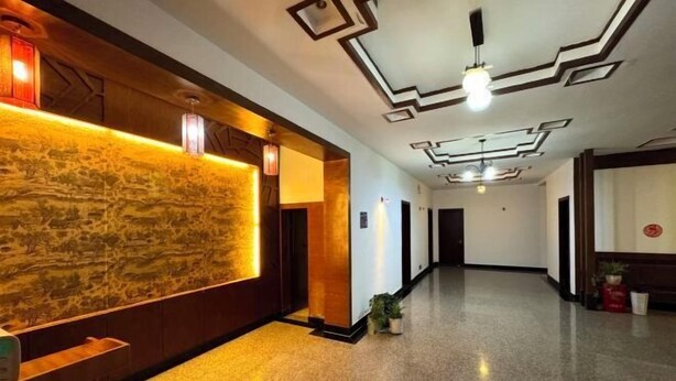 Zona de recepción de un hotel con pared de piedra, paneles de madera y suelo pulido.