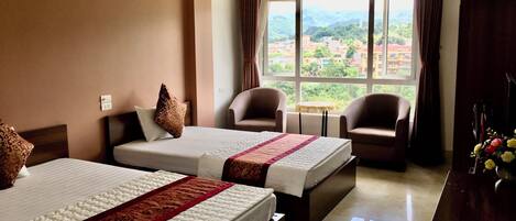 A hotel room with two beds, a small table, and two armchairs.