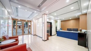Un área de recepción moderna con entrada de vidrio, mostrador de recepción y zona de estar.