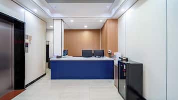 A hotel reception area with a reception desk, computers, and a small counter.