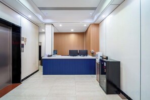 Zona de recepción de hotel con mostrador, computadoras y un pequeño mostrador.