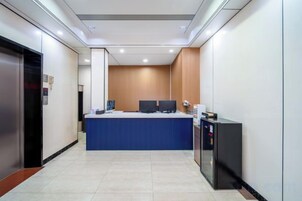Zona de recepción de hotel con mostrador, computadoras y un pequeño mostrador.