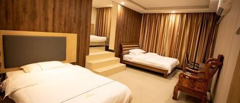 A hotel room with a large bed, a smaller bed, a wooden chair, a staircase, and a wooden wall panel.
