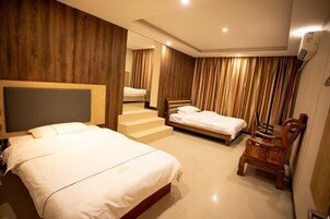 A hotel room with a large bed, a smaller bed, a wooden chair, a staircase, and a wooden wall panel.