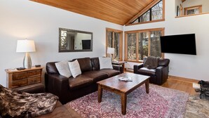 A spacious living room with a wooden ceiling, large windows, a flat-screen TV, leather sofas, and a coffee table. - Nowhere Land with Wintergreen Advantage (Wintergreen)