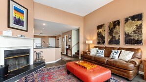 A living room with a fireplace, a brown leather sofa, a red ottoman, and a patterned rug. - Shenandoah Ridge 11 with Wintergreen Advantage (Wintergreen)