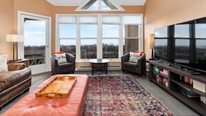 A living room with a large window, a TV, a sofa, and a coffee table. - Shenandoah Ridge 11 with Wintergreen Advantage (Wintergreen)