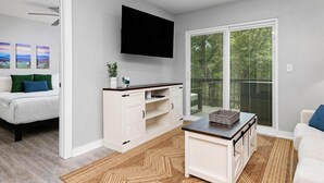 A modern living room with a flat-screen TV, a white sofa, a coffee table, and a sliding glass door leading to a balcony. - Gum Tree 5 with Wintergreen Advantage (Wintergreen)