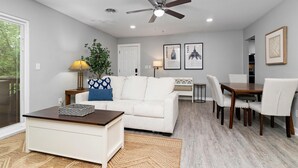 A modern living room with a white sofa, a coffee table, a dining table with chairs, a ceiling fan, and framed pictures on the wall. - Gum Tree 5 with Wintergreen Advantage (Wintergreen)