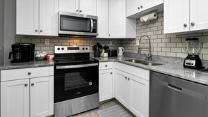 A modern kitchen with white cabinets, a stainless steel stove, a microwave, a dishwasher, and a granite countertop. - Gum Tree 5 with Wintergreen Advantage (Wintergreen)