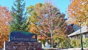 Une enseigne pour le Mountain Inn, avec une base en pierre et des fleurs aux couleurs vives.