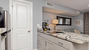 A compact kitchen with a white door, a countertop with a sink, and a small dining area with a table and chairs. - Timbers Lodge 42 with Wintergreen Advantage (Wintergreen)
