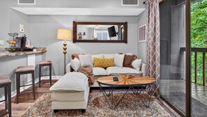 A modern living room with a sofa, ottoman, coffee table, and bar area with stools. - Timbers Lodge 42 with Wintergreen Advantage (Wintergreen)