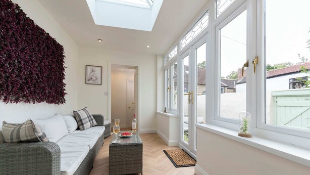 Een moderne woonkamer met een hoge plafond, een groot raam en uitzicht op het buiten.