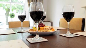 Een eettafel met drie wijnglazen, een kaasplankje en wat crackers, en een kleine potplant op de achtergrond.