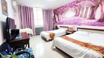 Habitación de hotel con dos camas, un escritorio con computadora, una silla y un gran mural floral en la pared.