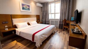 A hotel room with a bed, bedside tables, a desk, a television, and a window with curtains.