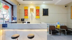 A hotel reception area with a marble counter, two bar stools, a table with chairs, and traditional decorations.